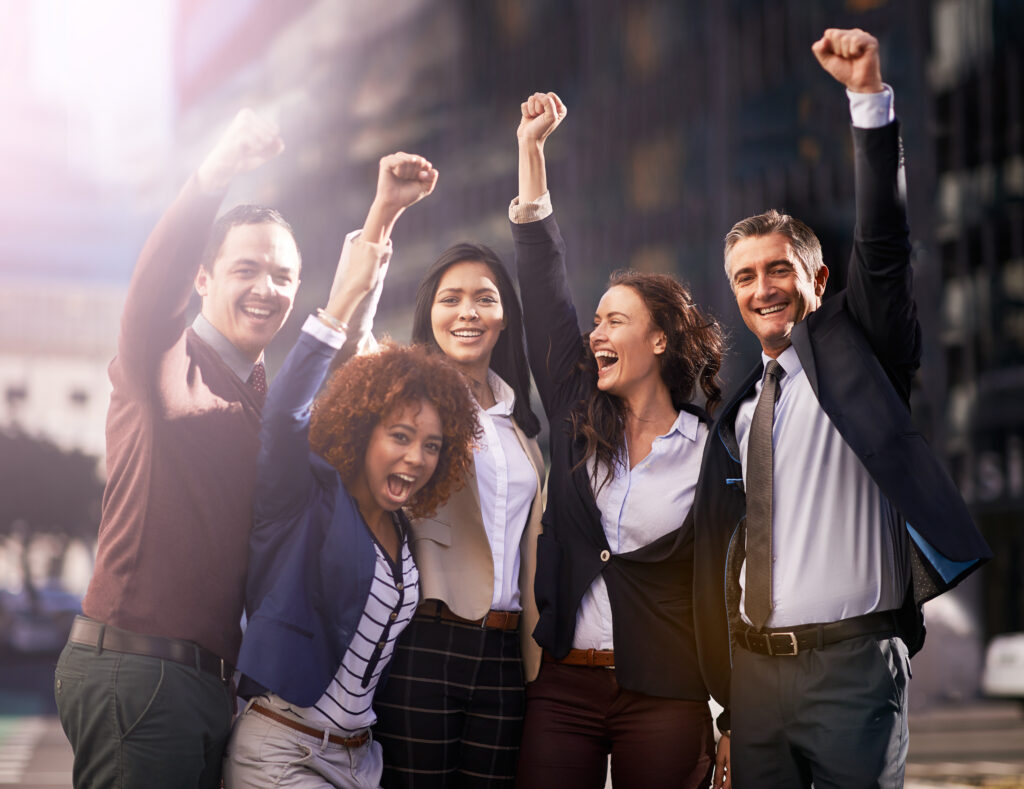 Diverse team raising their hands in victory, showcasing team success.